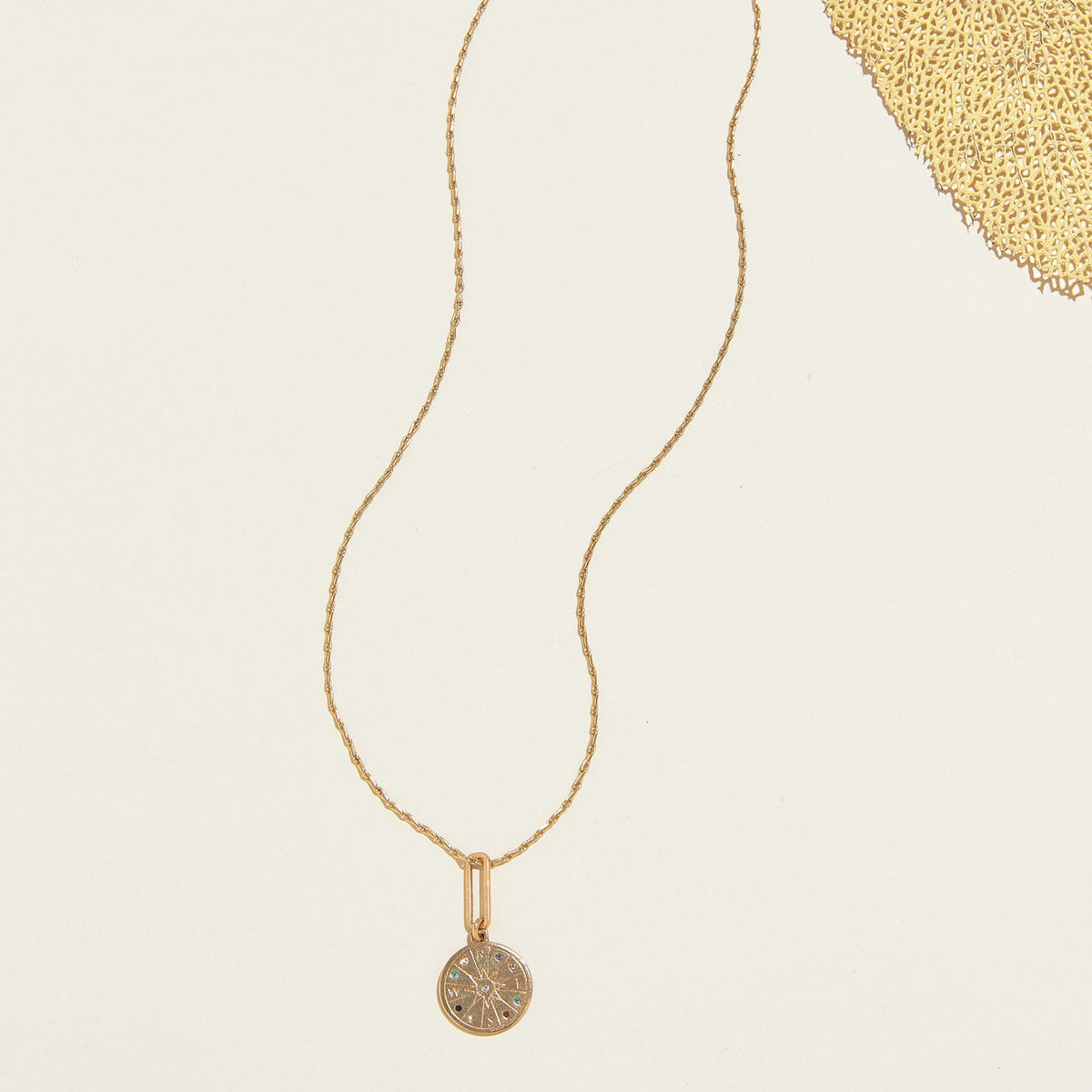 Gold Seeker Necklace by Mignonne Gavigan featuring a compass pendant with multicolored crystals on a gold chain.