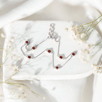 Bezel set garnet seven-stone station chain bracelet by Rosec Jewels showcasing sparkling red gemstones on a delicate gold chain.