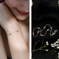 Bezel set garnet seven-stone station chain bracelet by Rosec Jewels featuring alternating deep red garnet stones on a silver chain.