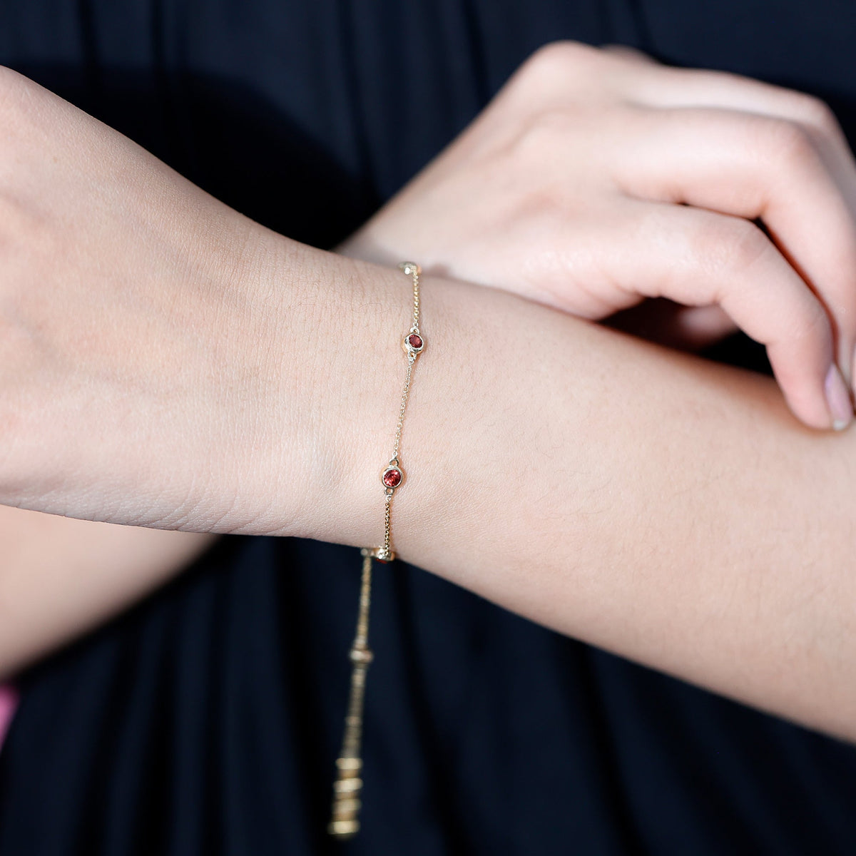 Bezel set garnet seven stone station chain bracelet by Rosec Jewels, featuring a delicate gold bracelet with sparkling garnet stones.