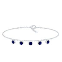 Bezel set blue sapphire charm bracelet by Rosec Jewels featuring a delicate silver chain with blue sapphire accents.