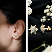 Rosec Jewels Moissanite winter snowflake stud earrings with sparkling gemstone details on silver-toned metal.