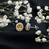 Natural 6x8mm oval citrine stud earrings with halo setting from Rosec Jewels, showcasing sparkling yellow gemstones.