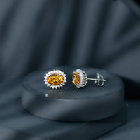 Natural 6x8mm oval citrine stud earrings with halo setting by Rosec Jewels, showcasing the sparkling yellow gemstones.