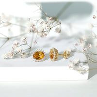 Natural 6x8mm oval citrine stud earrings with halo setting from Rosec Jewels, showcasing the sparkling yellow gemstones.