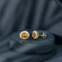 Natural 6x8mm oval citrine stud earrings with halo setting by Rosec Jewels, showcasing sparkling yellow-orange gemstones.