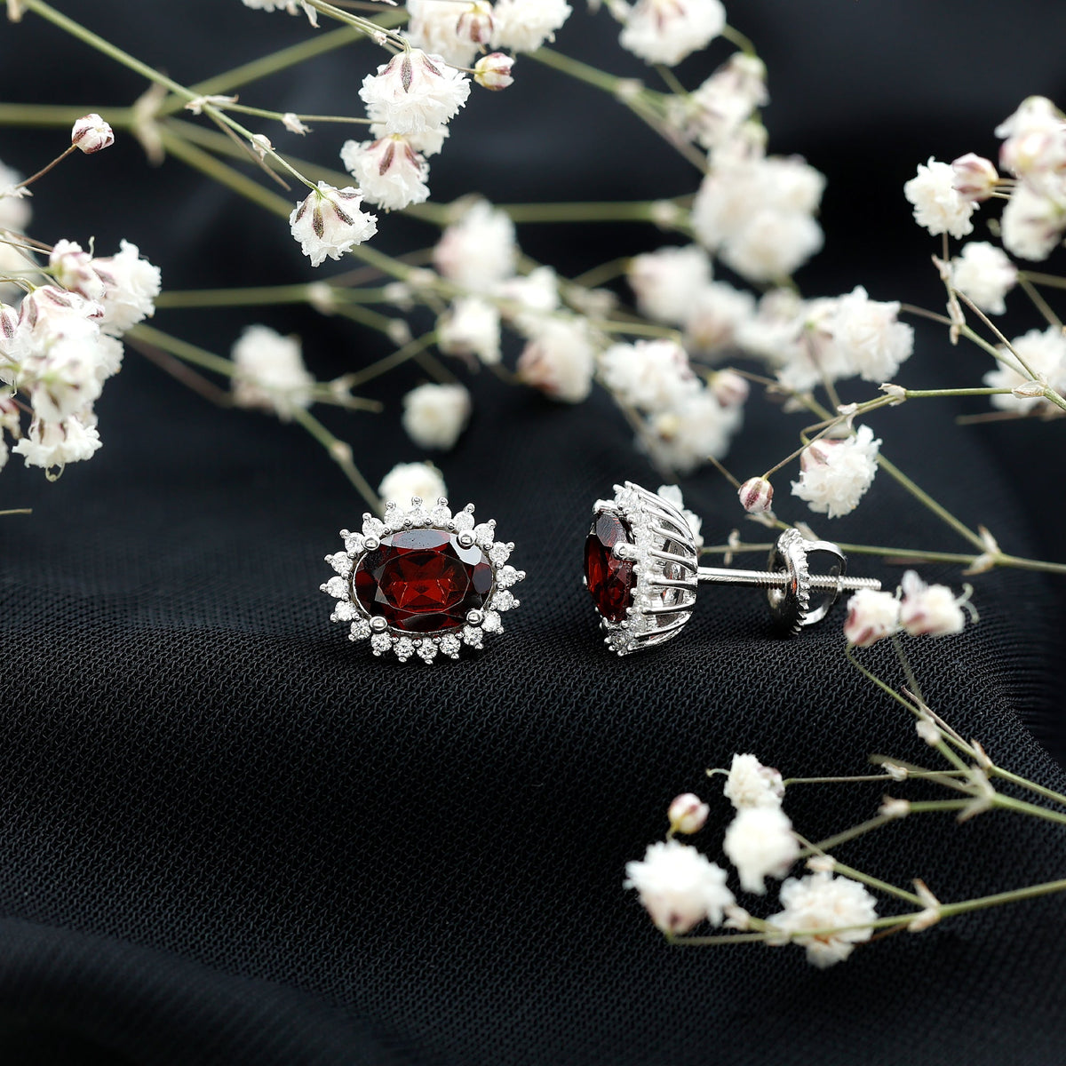 Oval garnet stud earrings with a moissanite halo, featuring Rosec Jewels branding, displayed on a white background.