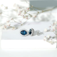 Rosec Jewels 6x8mm oval London Blue Topaz stud earrings with Moissanite halo, showcasing elegant gemstone and sparkling accent stones.