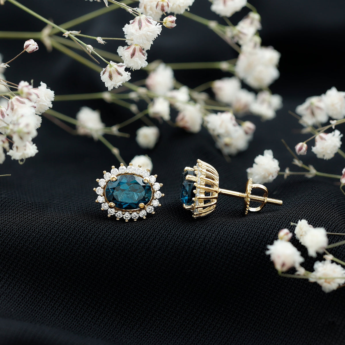 Rosec Jewels 6x8mm oval London Blue Topaz stud earrings with moissanite halo, showcasing elegant blue gemstones and sparkling accents.
