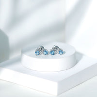 Rosec Jewels real aquamarine infinity stud earrings with sparkling blue gemstones on silver posts.
