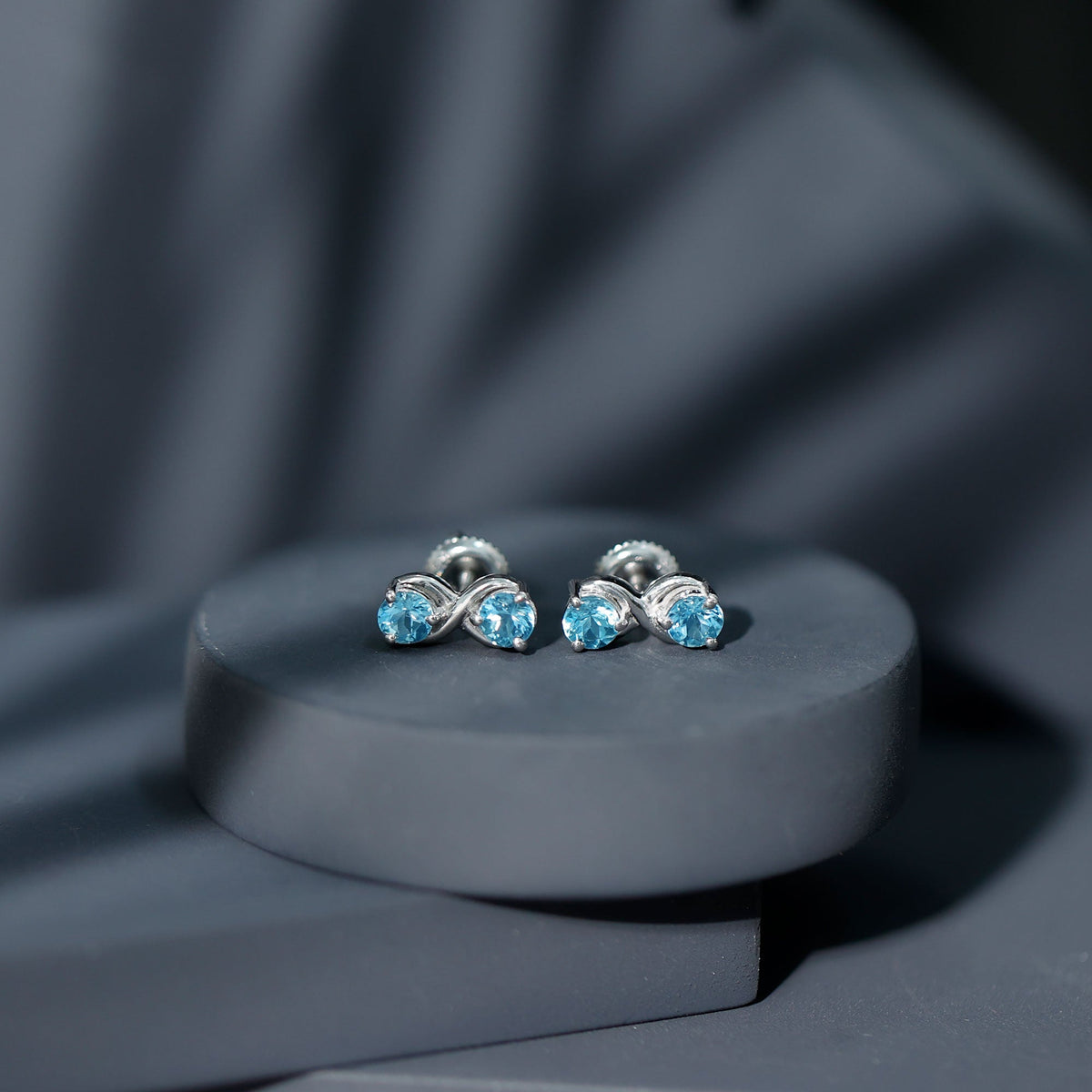Real aquamarine infinity stud earrings by Rosec Jewels featuring sparkling blue gemstones and silver posts.