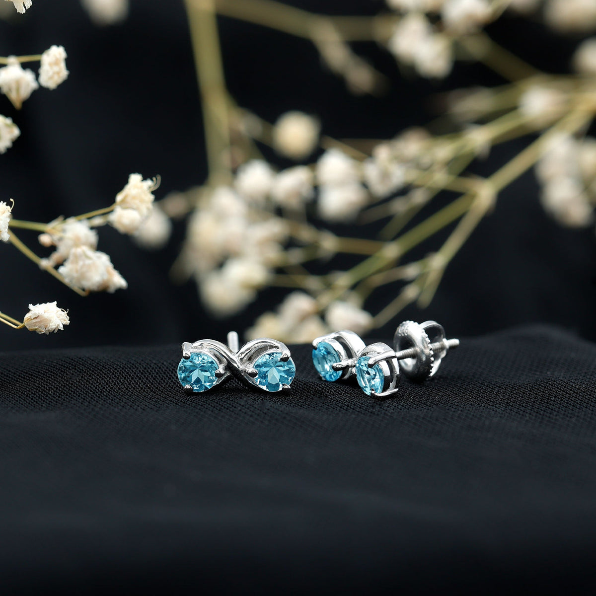 Rosec Jewels real aquamarine infinity stud earrings featuring sparkling blue gemstones and sleek silver settings.