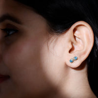 Real aquamarine infinity stud earrings by Rosec Jewels, featuring sparkling blue gemstone accents on silver posts.