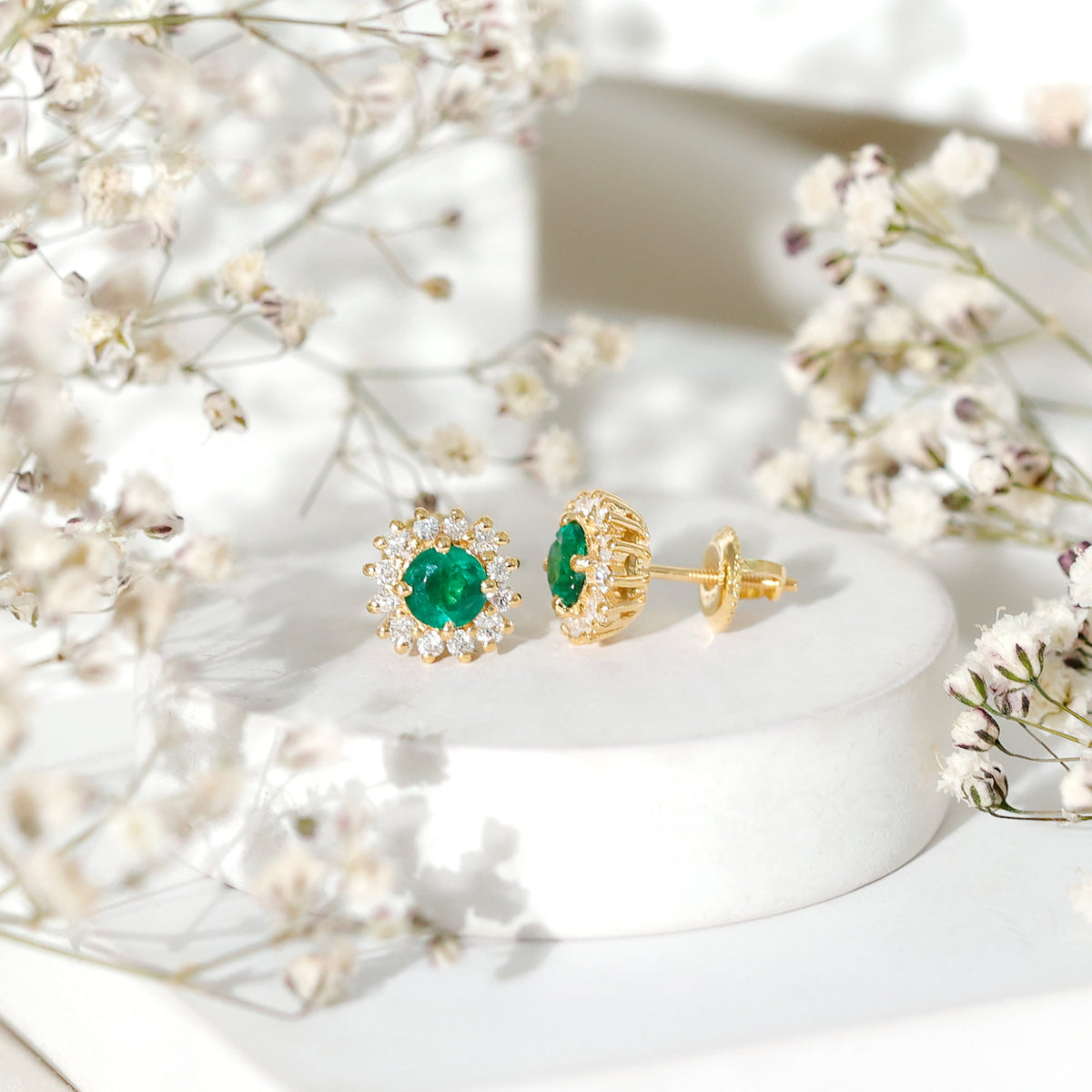 Elegant emerald stud earrings with diamond halo from Rosec Jewels, showcasing sparkling gemstones and a classic design.