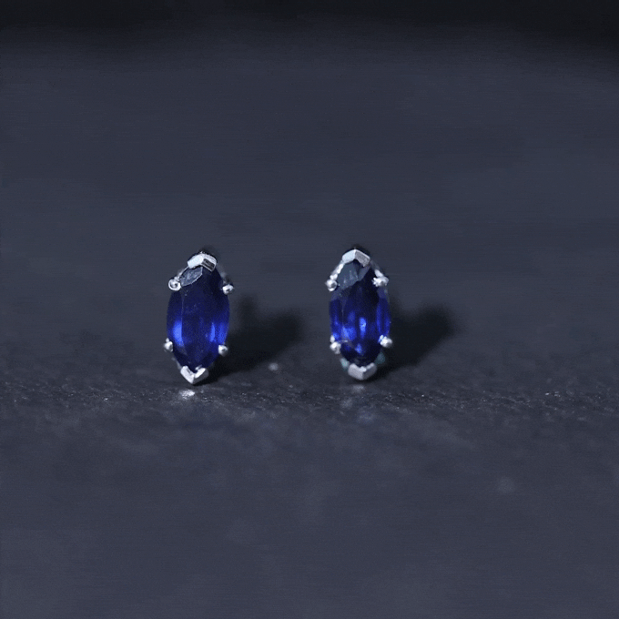 Yellow background image of Rosec Jewels 1.5 carat marquise lab-created blue sapphire stud earrings showing sparkling blue gemstones.
