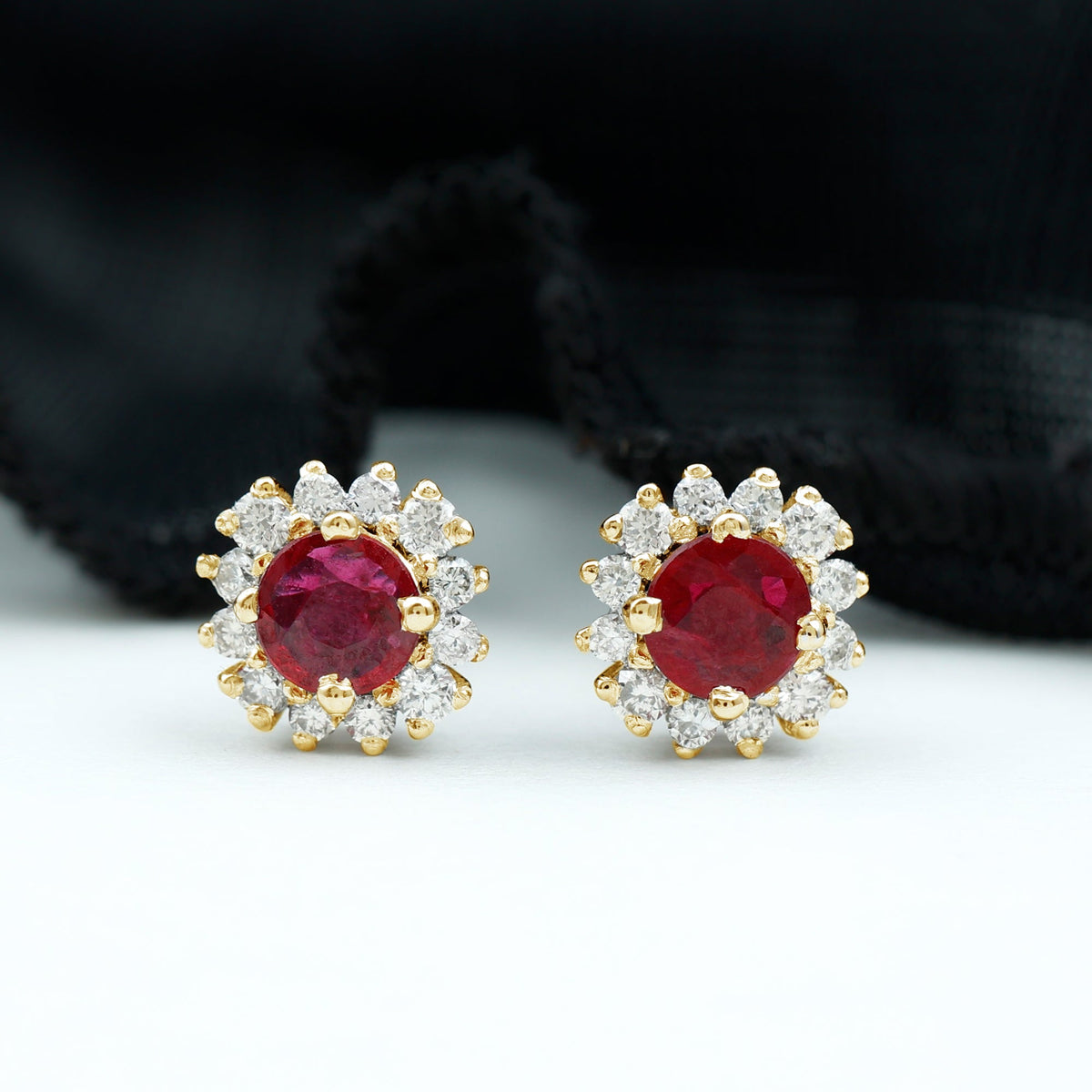 Genuine ruby stud earrings with diamond halo from Rosec Jewels, featuring vibrant red rubies surrounded by sparkling diamonds.