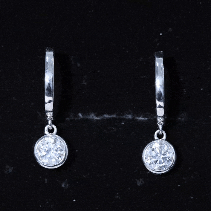 Bezel set 2 carat round Moissanite drop hoop earrings by Rosec Jewels featuring sparkling white stones and sleek gold hoops.