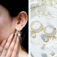 Bezel set moissanite and hinged hoop earrings by Rosec Jewels, featuring sparkling stones and a sleek gold finish.