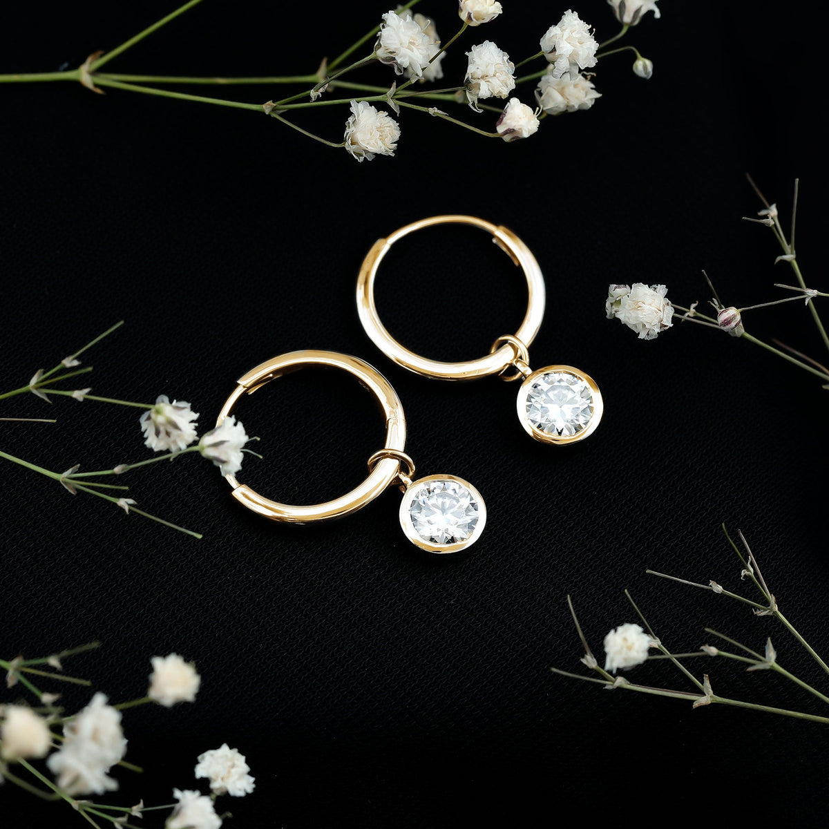 Bezel set moissanite and hinged hoop earrings by Rosec Jewels, featuring sparkling stones and a secure clasp on shiny gold hoops.