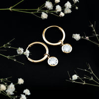 Bezel set moissanite and hinged hoop earrings by Rosec Jewels, featuring sparkling stones and a secure clasp on shiny gold hoops.
