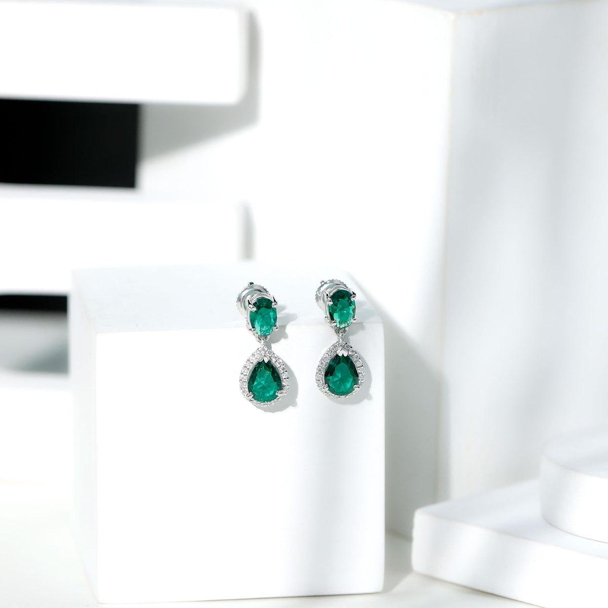 Lab-created emerald dangle earrings with moissanite accents from Rosec Jewels, featuring elegant silver hooks and intricate gemstone details.