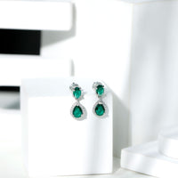 Lab-created emerald dangle earrings with moissanite accents from Rosec Jewels, featuring elegant silver hooks and intricate gemstone details.