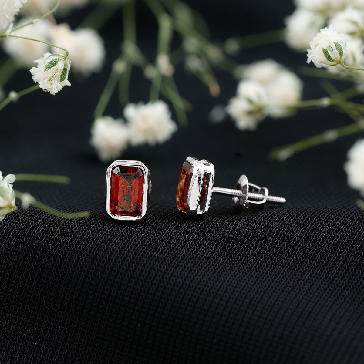 Emerald cut 1.4 CT garnet solitaire stud earrings in bezel setting by Rosec Jewels, showcasing the deep red gemstone and sleek design.