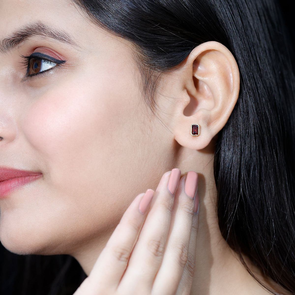 Emerald cut garnet solitaire stud earrings in bezel setting by Rosec Jewels, showcasing deep red gemstone on a sleek silver post