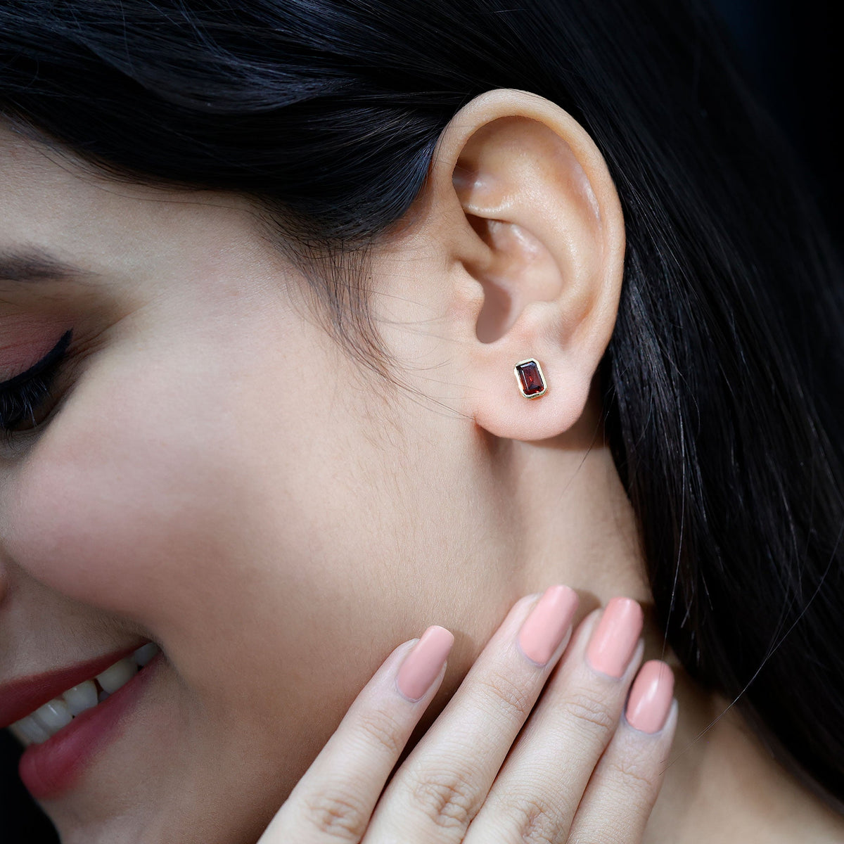 Emerald cut garnet solitaire stud earrings in bezel setting by Rosec Jewels, showcasing deep red gemstone and sleek metal design.