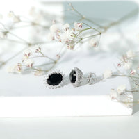 Oval cut black onyx stud earrings with a moissanite halo, featuring Rosec Jewels branding, displayed on a white background.