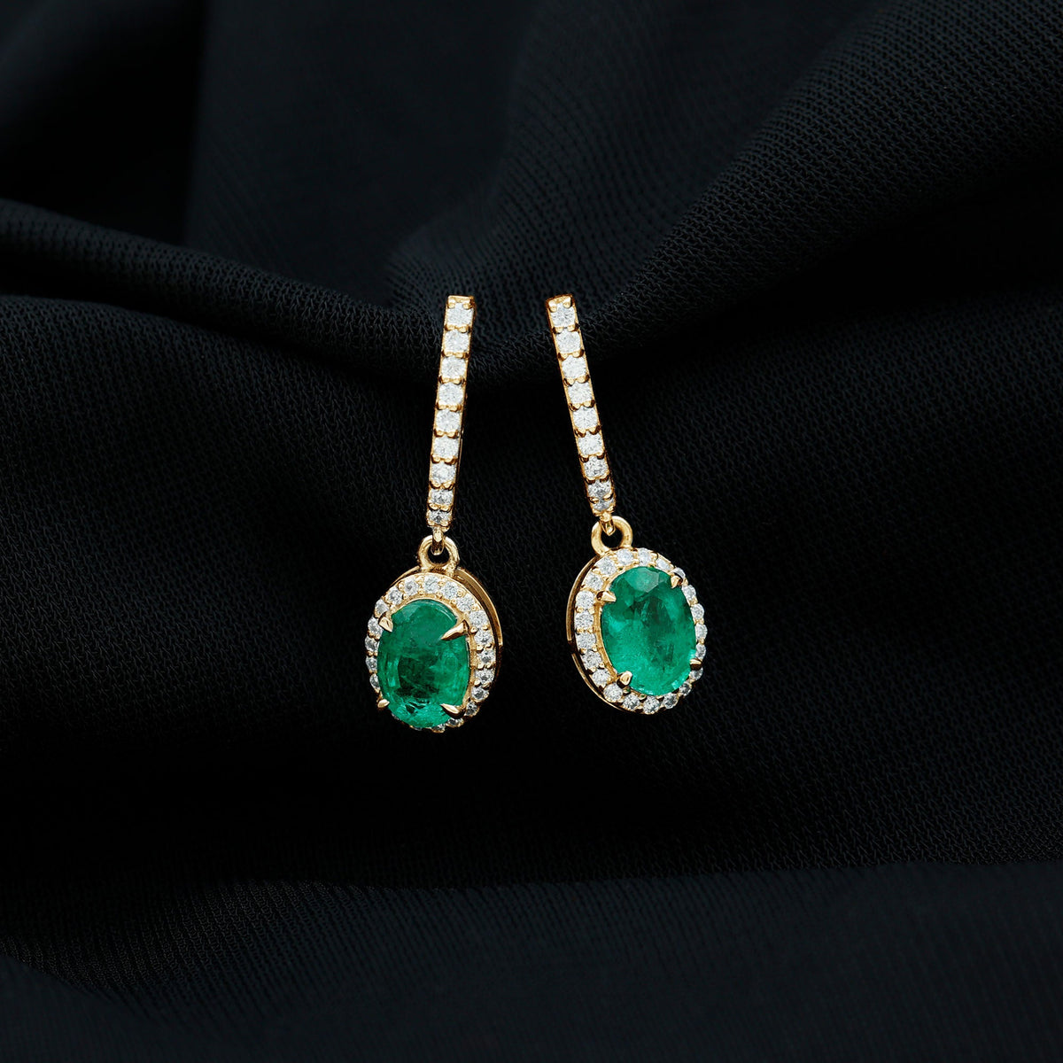 Oval shape emerald hoop earrings with diamond halo from Rosec Jewels, featuring elegant drop design and sparkling accents.