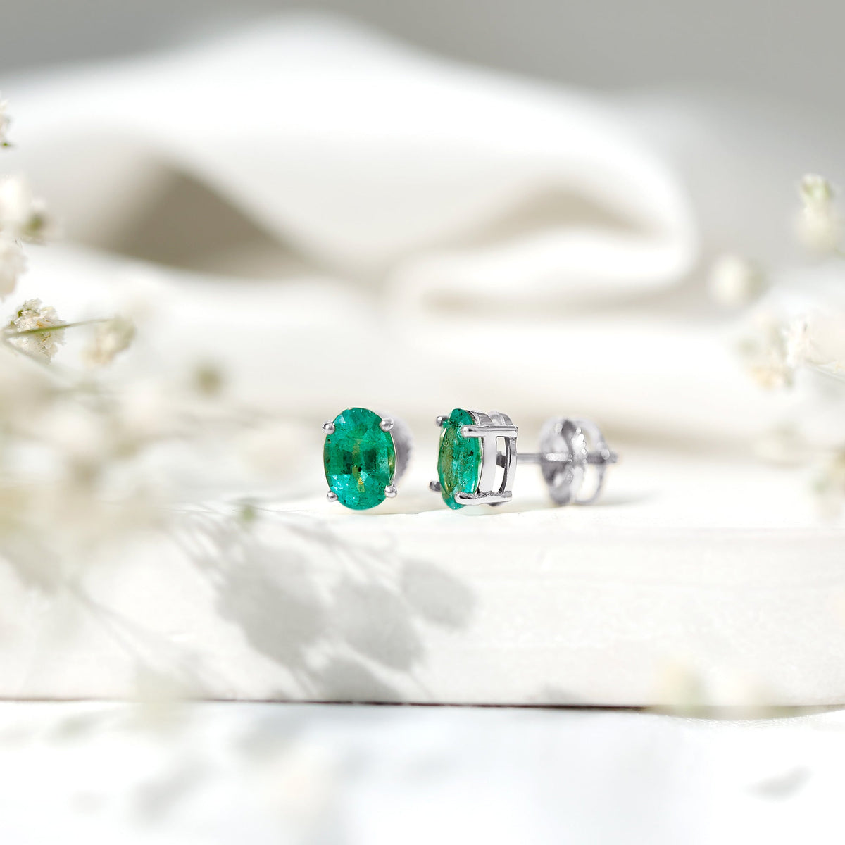Oval shape emerald stud earrings for women with 1.43 carats, featuring sparkling green emeralds and a classic earring design.
