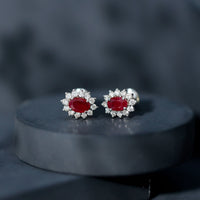 Genuine oval cut ruby and diamond halo stud earrings by Rosec Jewels featuring vibrant red rubies surrounded by sparkling diamonds.