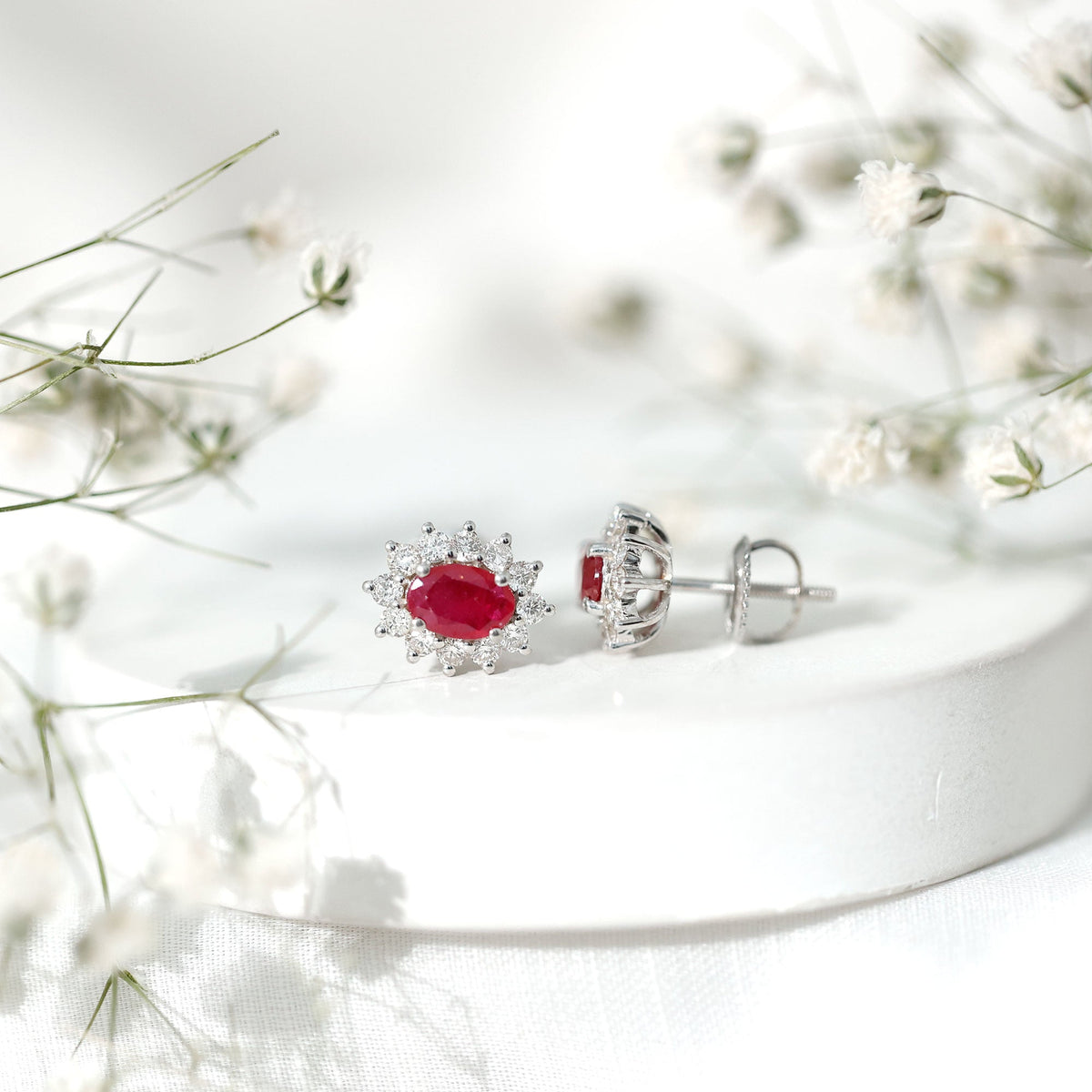 Genuine oval cut ruby and diamond halo stud earrings by Rosec Jewels featuring sparkling gemstones and elegant design.