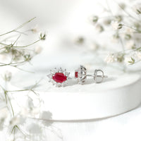 Genuine oval cut ruby and diamond halo stud earrings by Rosec Jewels featuring sparkling gemstones and elegant design.