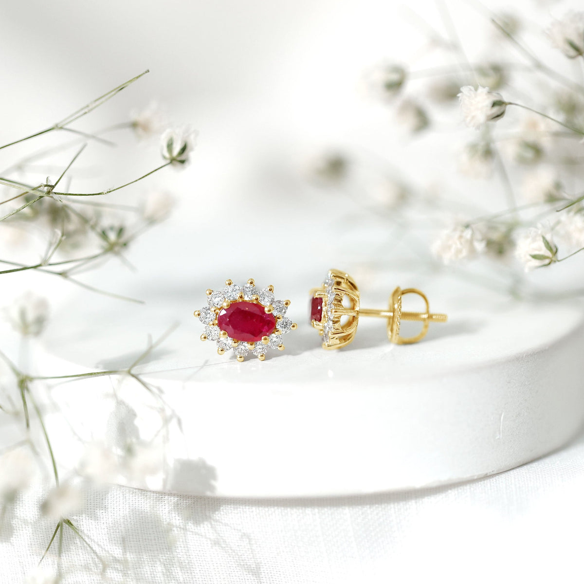 Genuine oval cut ruby and diamond halo stud earrings by Rosec Jewels featuring sparkling gemstones and a classic earring design.