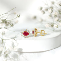 Genuine oval cut ruby and diamond halo stud earrings by Rosec Jewels featuring sparkling gemstones and a classic earring design.