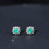 Real emerald stud earrings with diamond halo, featuring vibrant green gemstones and sparkling diamonds in elegant jewelry design.