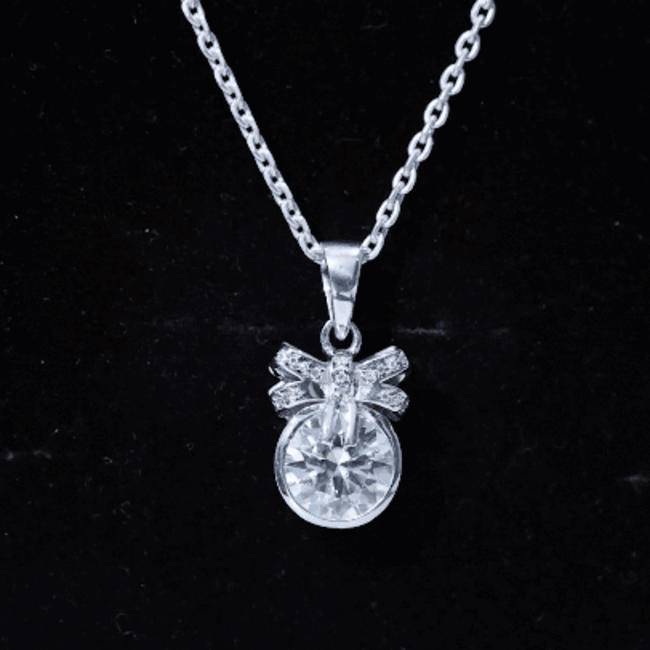 Yellow bezel set lab grown diamond solitaire pendant with a cute bow, featuring Rosec Jewels branding.
