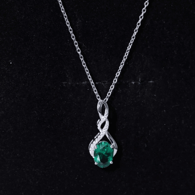 Lab-grown 1.25 carat emerald infinity pendant on silver chain, elegant jewelry featuring a sparkling green gemstone.
