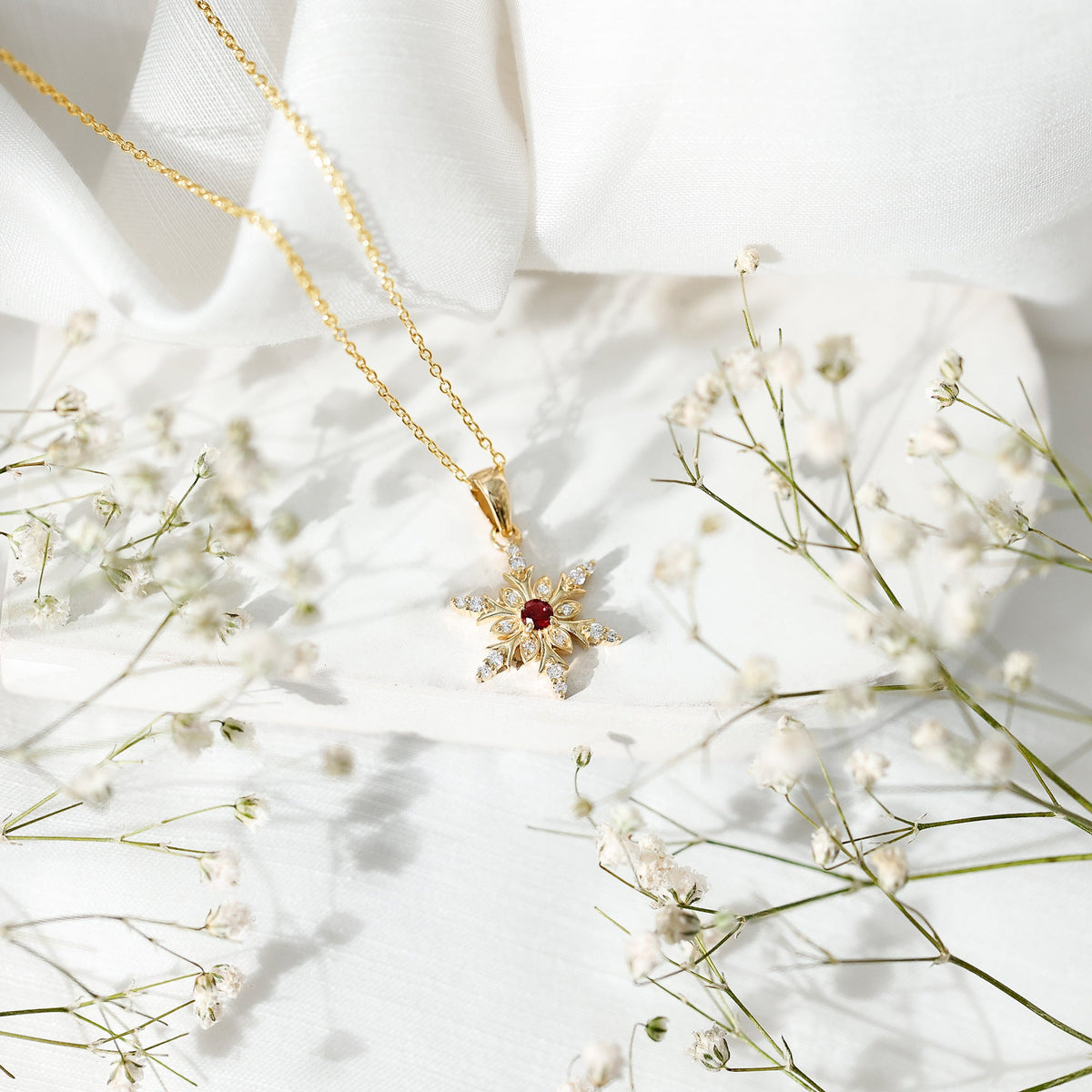 Lab created ruby snowflake pendant with diamond accents from Rosec Jewels, featuring intricate snowflake design in a pendant style.
