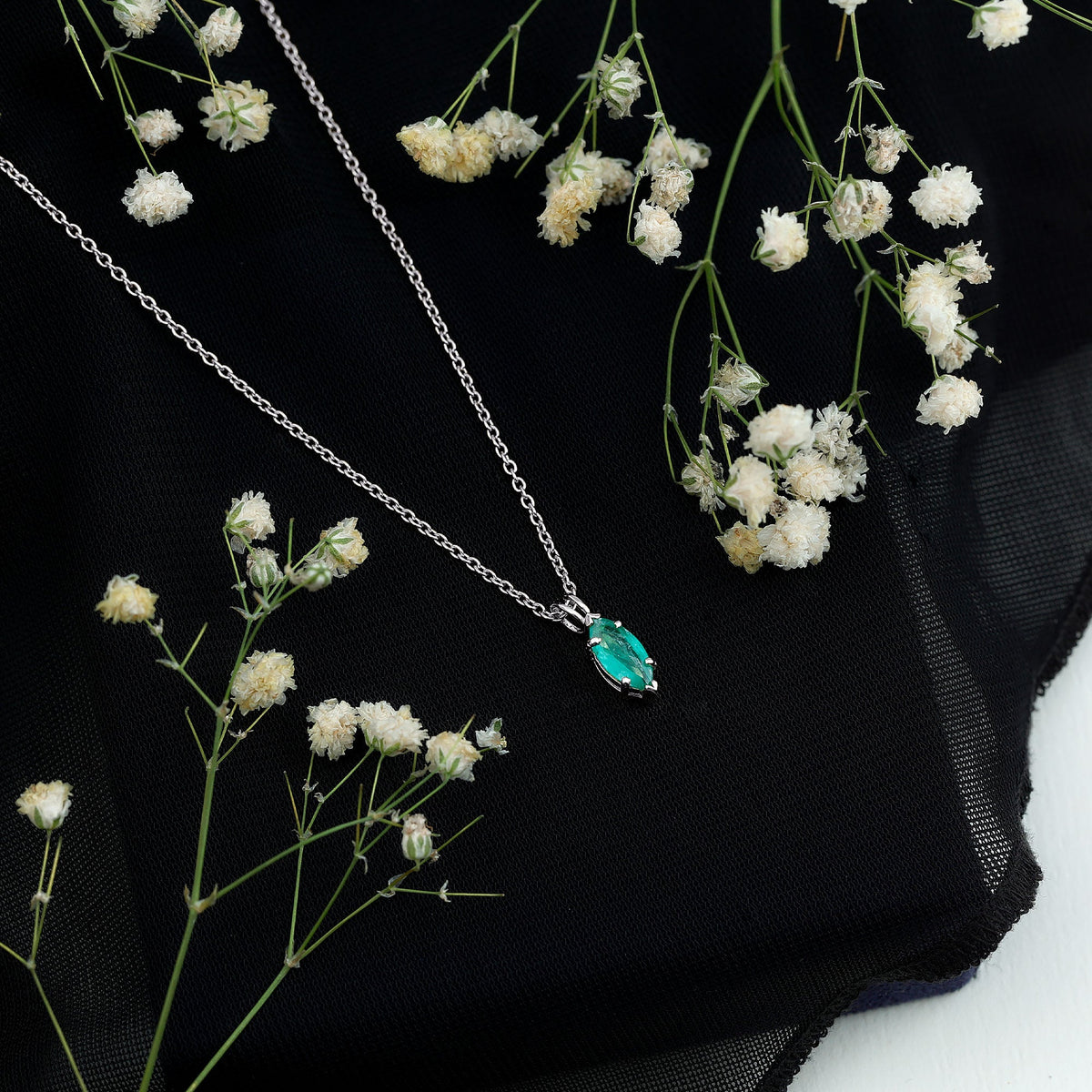 Marquise cut emerald solitaire pendant necklace with silver chain from Rosec Jewels, showcasing a vibrant green gemstone.