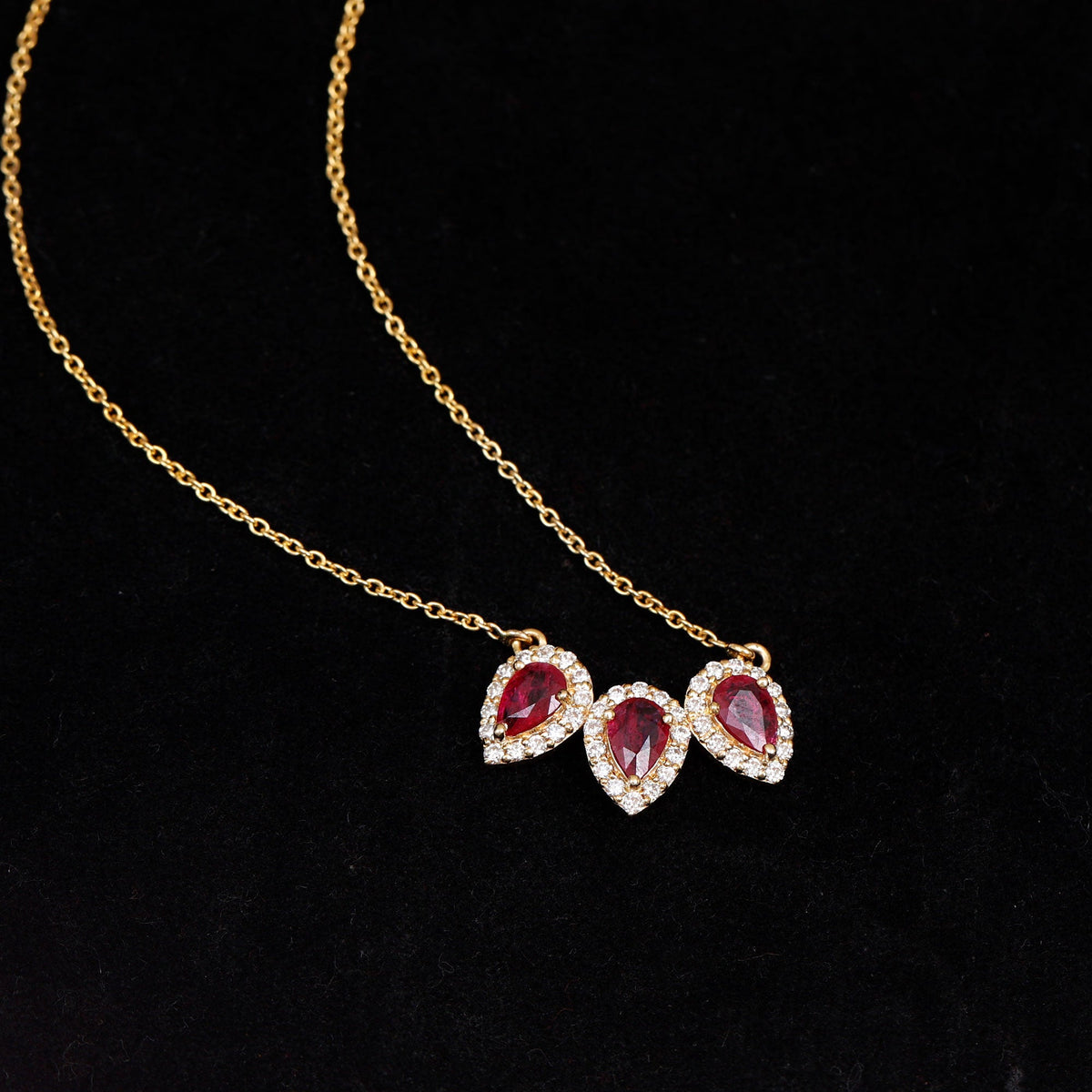 Pear cut lab-created ruby three-stone necklace with moissanite halo pendant by Rosec Jewels, showcasing elegant gemstone design.