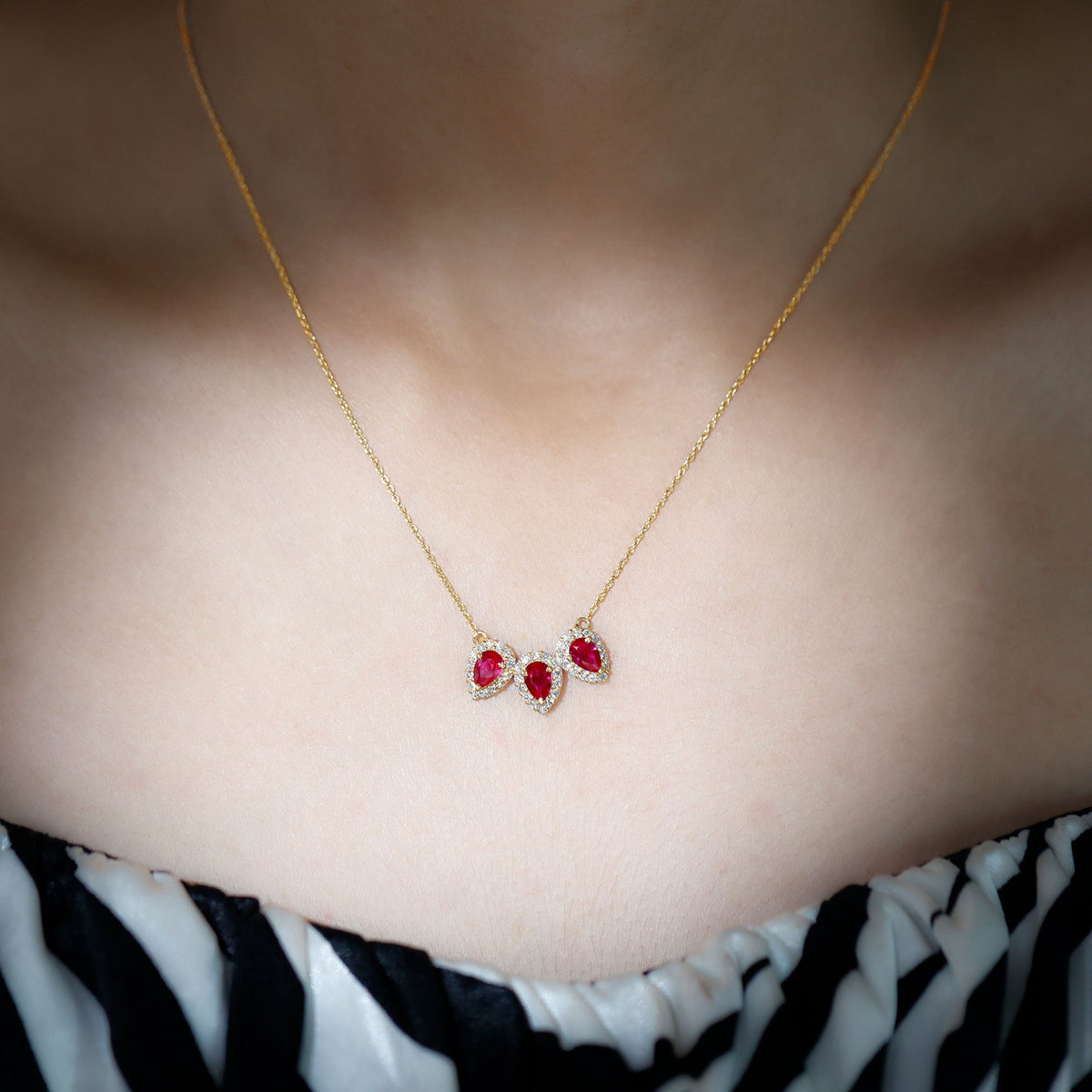 Pear cut lab-created ruby three-stone necklace with moissanite halo pendant from Rosec Jewels, showcasing sparkling gemstones and elegant design.