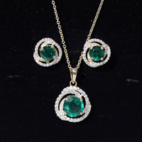 Lab-created emerald swirl necklace and earrings set with moissanite, featuring vibrant green gemstones and elegant jewelry design.