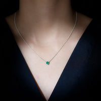 Emerald pendant with 5mm round cut solitaire in 6 prong setting, showcased in elegant jewelry image.