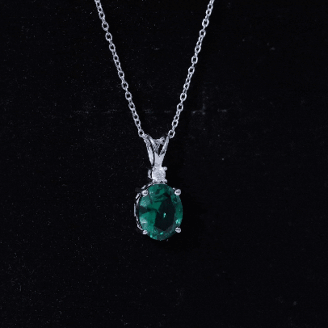 Oval lab-grown emerald pendant on silver chain, 8x10 mm solitaire necklace by Rosec Jewels, close-up view of the jewelry piece.