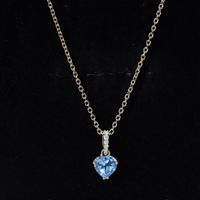 Yellow gold heart pendant featuring a 0.9 carat Swiss Blue Topaz solitaire and diamond accents on a chain.