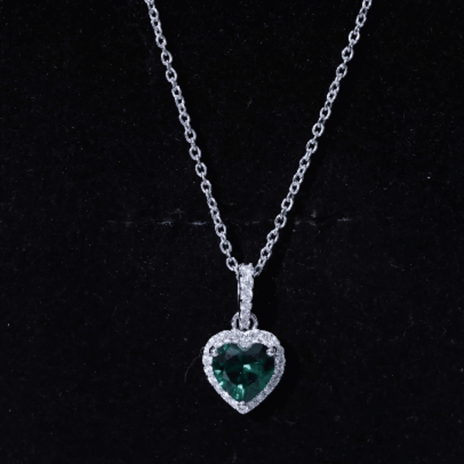 Lab grown 1.37 carat emerald heart pendant with moissanite halo, featuring a delicate silver chain and intricate detailing.