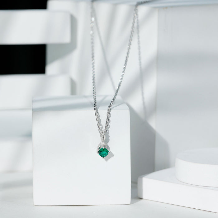 Cushion cut lab-created emerald infinity pendant on a silver chain, featuring a 0.9 carat vibrant green gemstone.